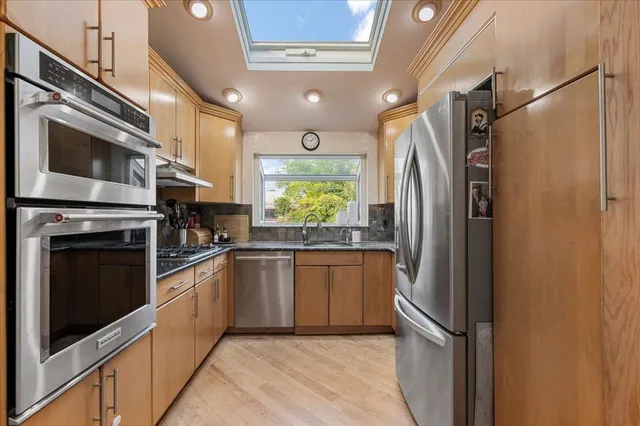 a kitchen with granite countertop stainless steel appliances a refrigerator cabinets and a sink