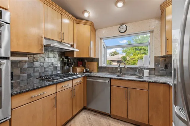 a kitchen with stainless steel appliances granite countertop a sink a stove and cabinets