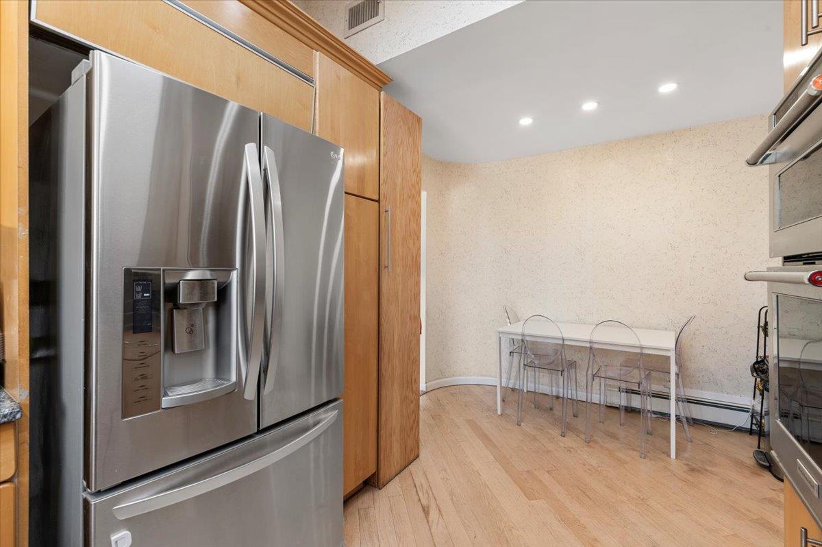 722 Eagle Drive Valley Stream, NY 11581 - Photo 13 of 35 a view of a refrigerator in kitchen and an empty room with wooden floor