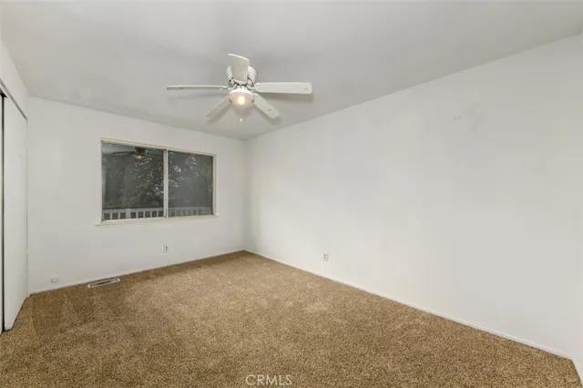 an empty room with a window and a ceiling fan