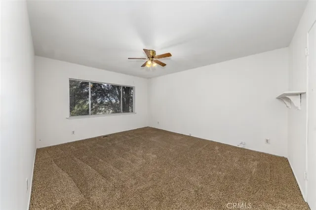 an empty room with window and a ceiling fan