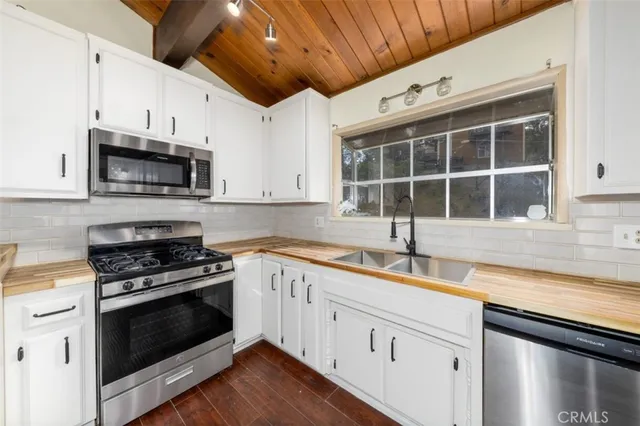 a kitchen with granite countertop a sink cabinets stainless steel appliances and a counter space