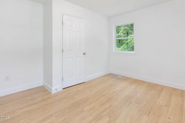 an empty room with wooden floor and window