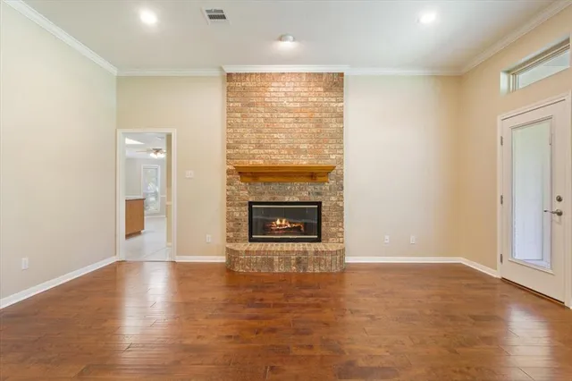an empty room with wooden floor a fireplace and windows
