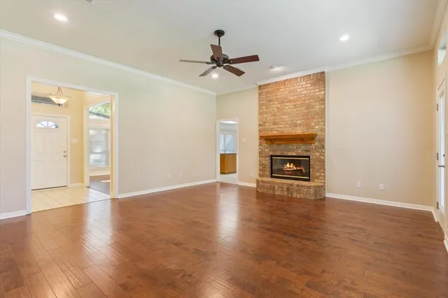 an empty room with wooden floor fireplace and windows