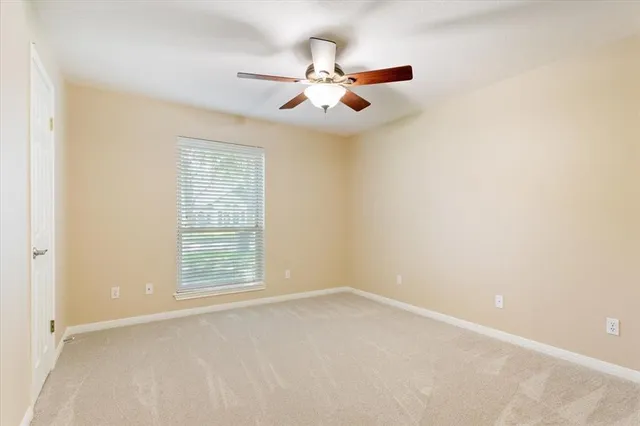 an empty room with a window and a fan