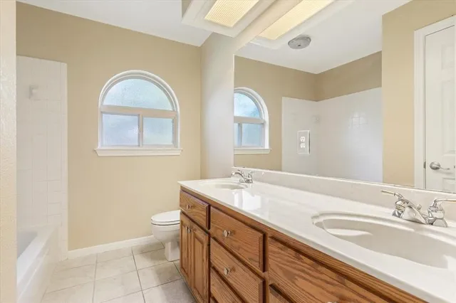 a bathroom with a granite countertop double vanity sink a mirror and a toilet