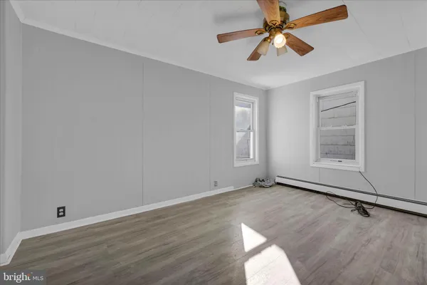 an empty room with wooden floor ceiling fan and windows