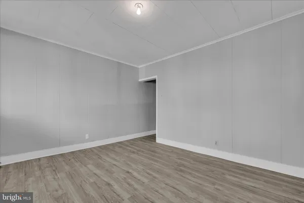 a view of an empty room with wooden floor and closet