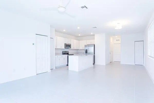 a view of kitchen with refrigerator and white cabinets