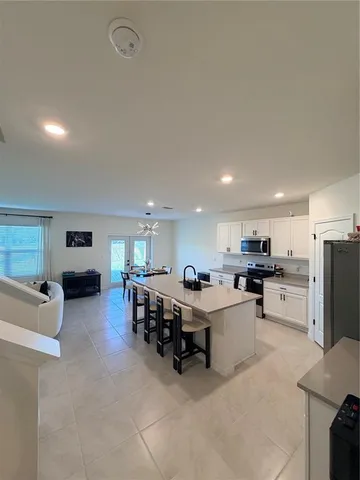 a large white kitchen with a large counter top furniture and stainless steel appliances