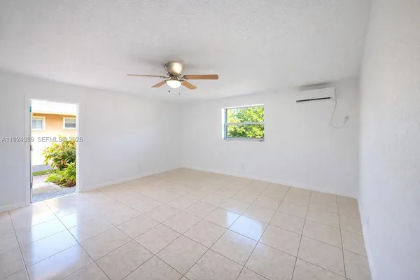 an empty room with windows and chandelier fan