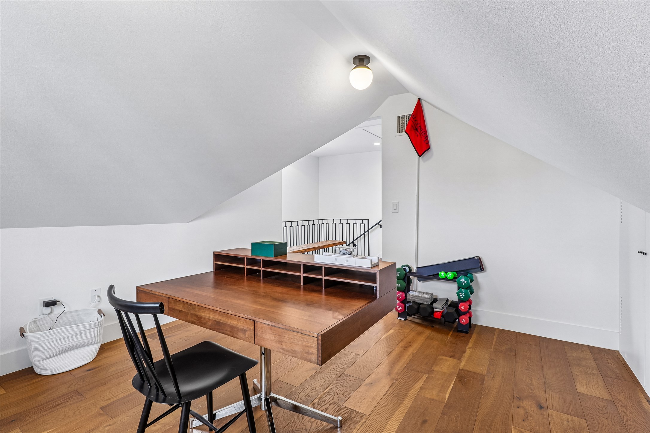 1706 Perez Street, Unit 1 Austin, TX 78721 - Photo 23 of 36 An inviting attic retreat offers rich hardwood flooring and sloped ceilings, perfect for a home office or creative space.