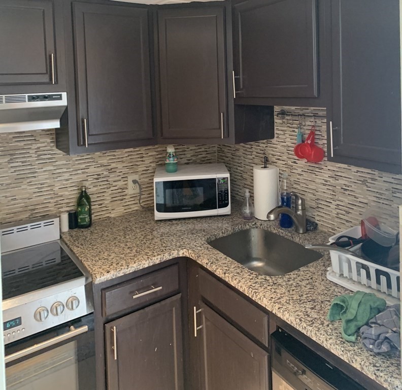 464 Commonwealth Avenue, Unit 36 Boston, MA 02215 - Photo 5 of 22 a kitchen with granite countertop stainless steel appliances sink stove microwave and cabinets