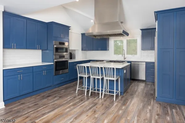 a kitchen with kitchen island granite countertop wooden floors a stove and a sink