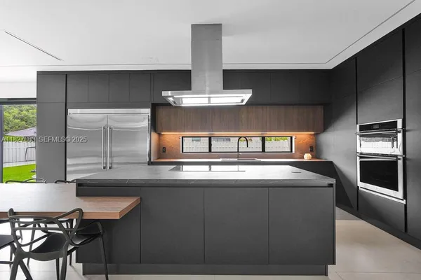 a kitchen with a table chairs stainless steel appliances and cabinets
