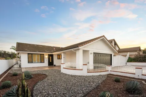 a view of a house with a small yard and large tree