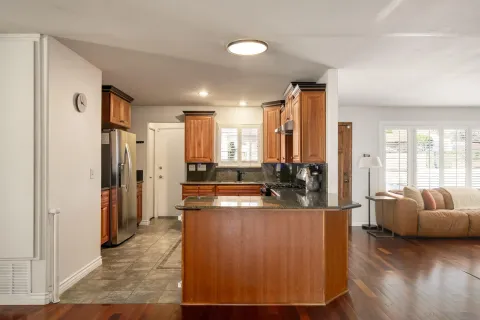 a large living room with stainless steel appliances granite countertop a couch and a large window