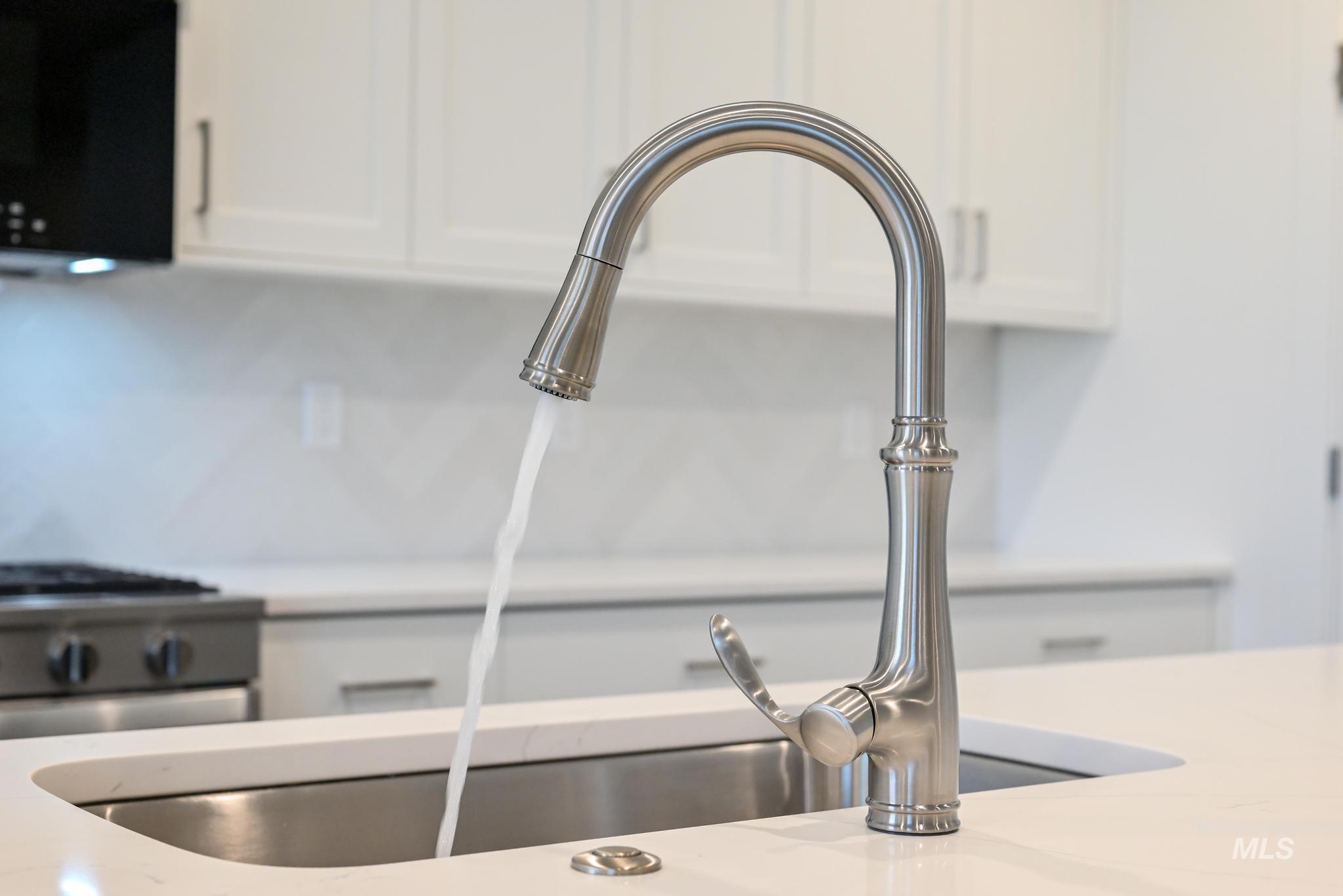 5923 West Snow Currant Street Meridian, ID 83646 - Photo 13 of 28 Kitchen view of white cabinetry, stainless steel gas stove, and light stone countertops