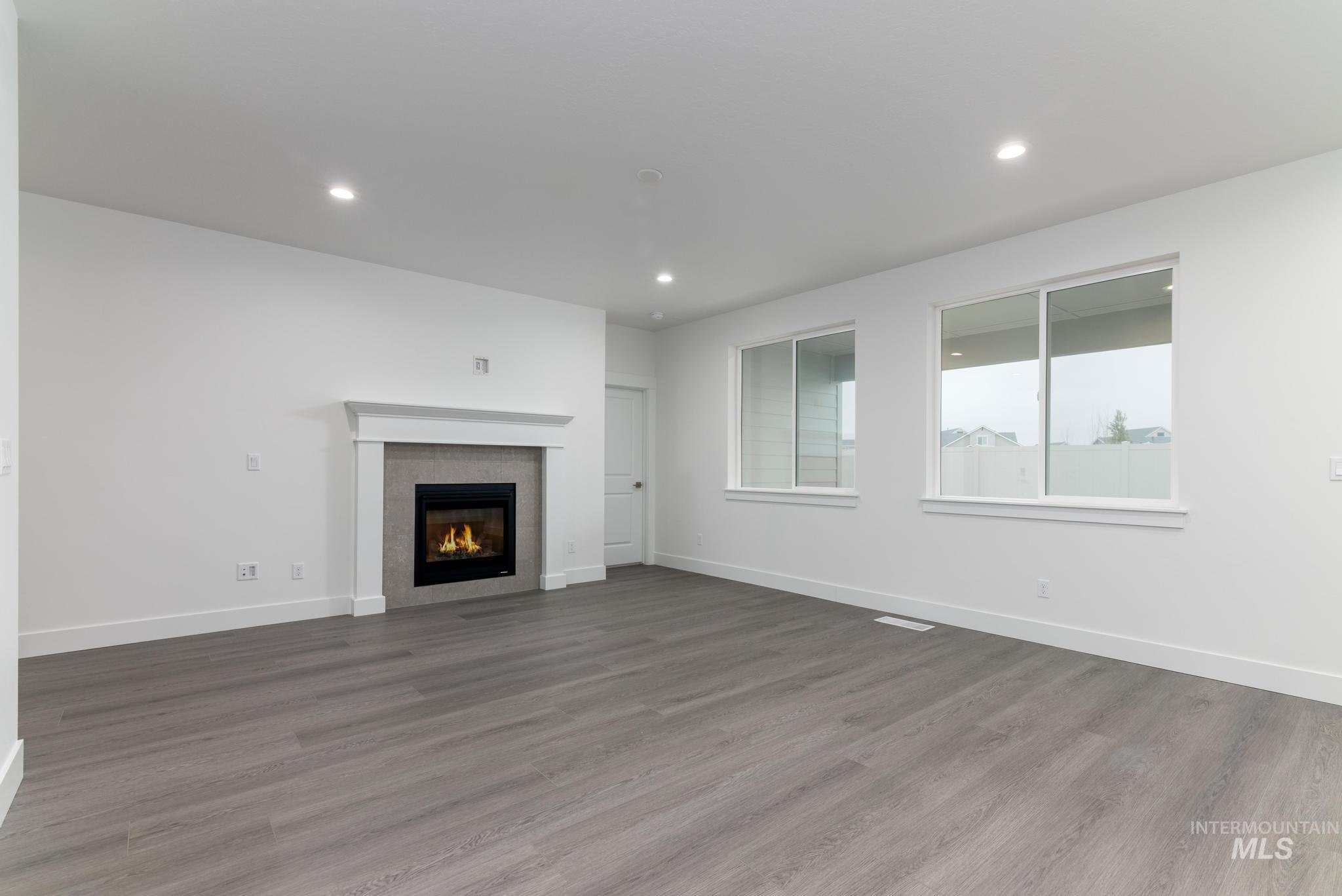 5923 West Snow Currant Street Meridian, ID 83646 - Photo 5 of 28 Unfurnished living room featuring a tiled fireplace, light wood finished floors, and recessed lighting