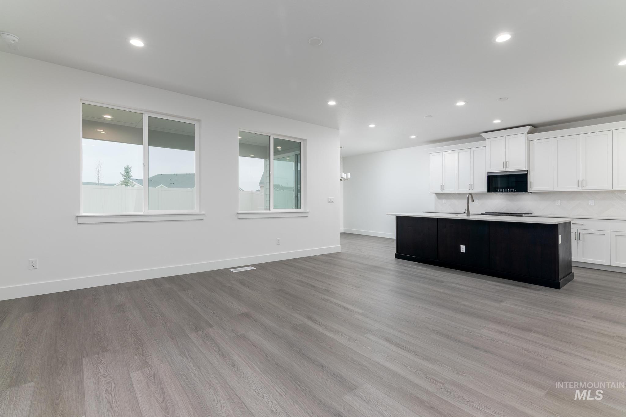 5923 West Snow Currant Street Meridian, ID 83646 - Photo 28 of 28 Kitchen with white cabinets, a center island with sink, open floor plan, light wood-style floors, and recessed lighting