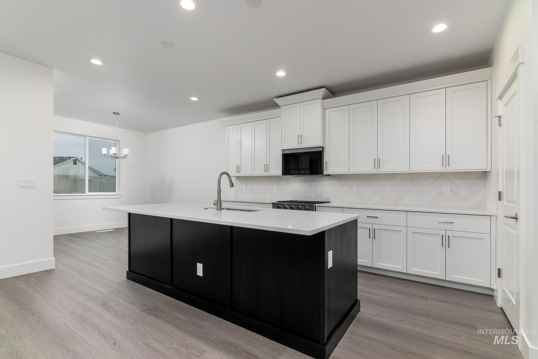 5923 West Snow Currant Street Meridian, ID 83646 - Photo 8 of 28 Kitchen with dark cabinets, decorative light fixtures, white cabinets, an island with sink, and recessed lighting