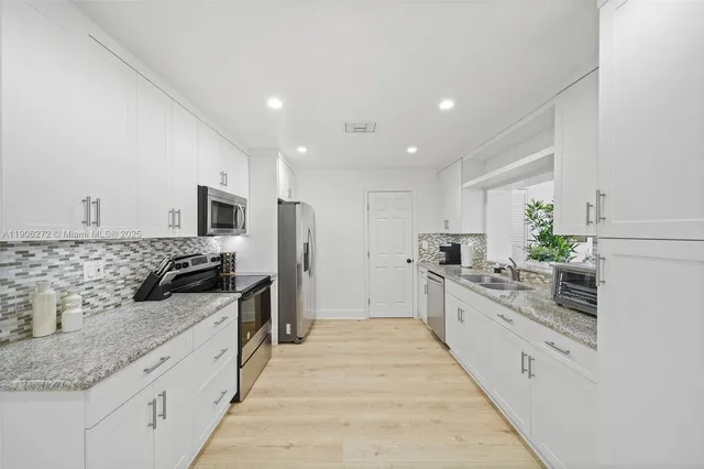 a large kitchen with stainless steel appliances kitchen island granite countertop a large counter top and white cabinets