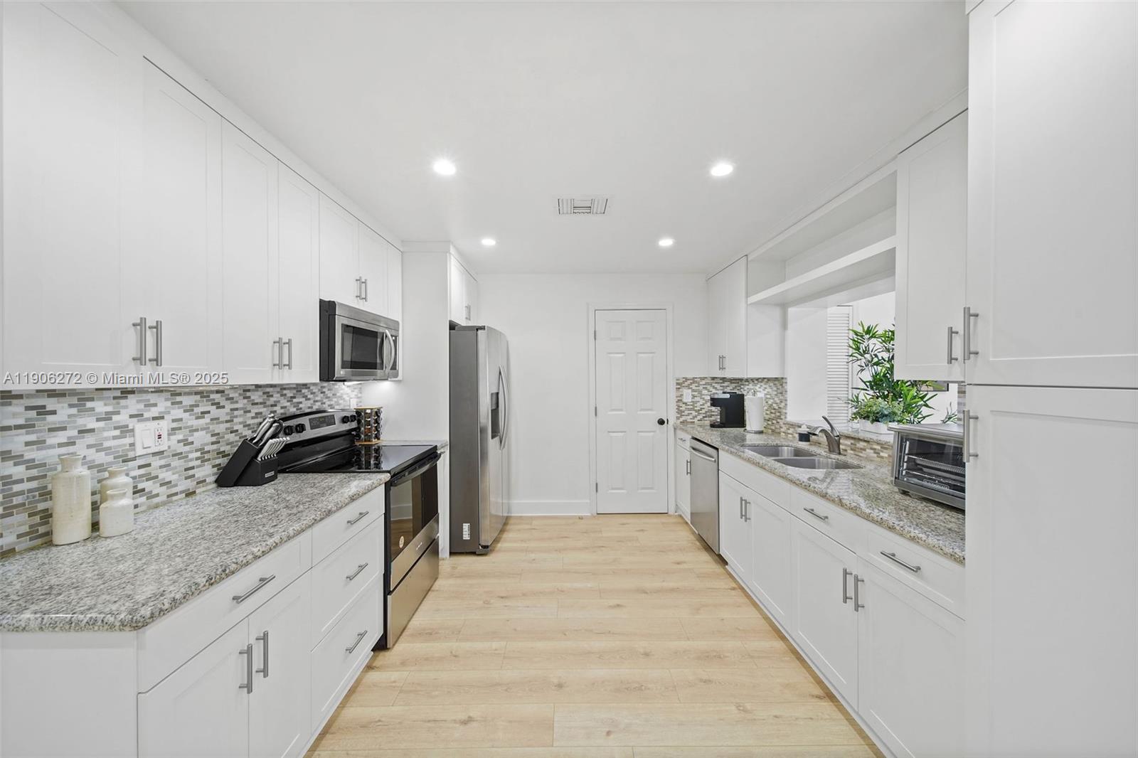 2761 Southwest 92nd Place Miami, FL 33165 - Photo 3 of 19 a large kitchen with stainless steel appliances kitchen island granite countertop a large counter top and white cabinets