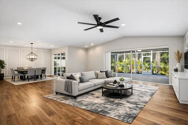 a view of an empty room with wooden floor and a ceiling fan
