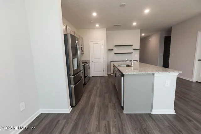 a kitchen with wooden floor sink and refrigerator