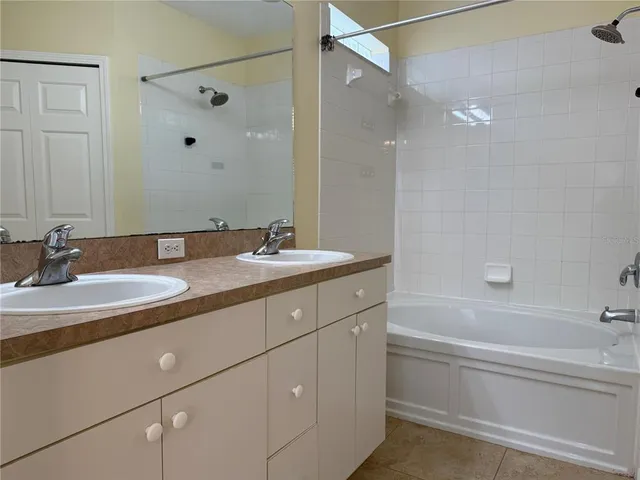 a bathroom with a sink double vanity granite tub shower and a mirror