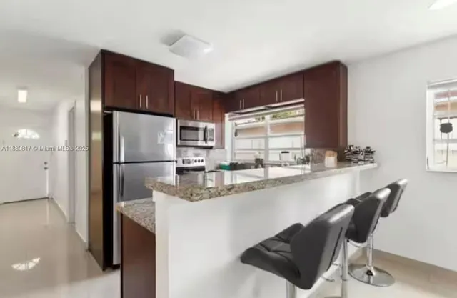 a kitchen with kitchen island a counter top space cabinets and stainless steel appliances
