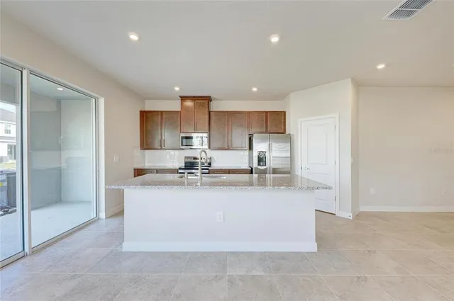 a large kitchen with stainless steel appliances granite countertop a sink a refrigerator and a granite counter tops