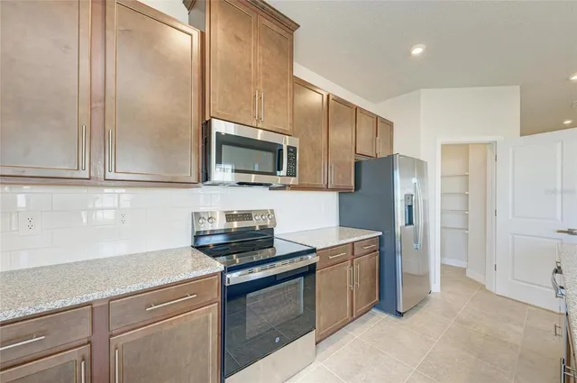 a kitchen with stainless steel appliances granite countertop a refrigerator a sink a stove a microwave and wooden cabinets