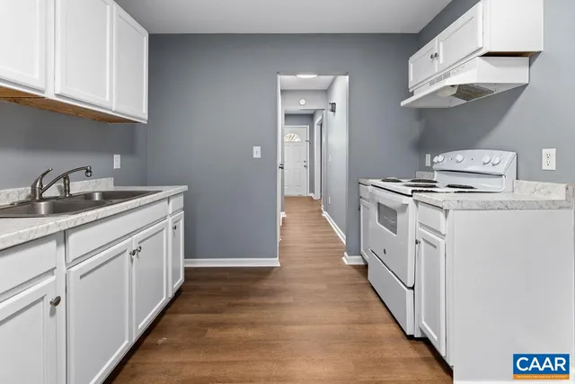 a kitchen with white cabinets sink and stove