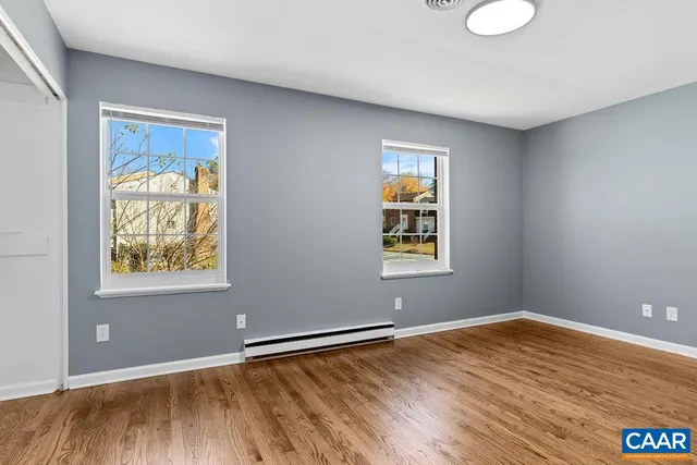 an empty room with wooden floor and windows
