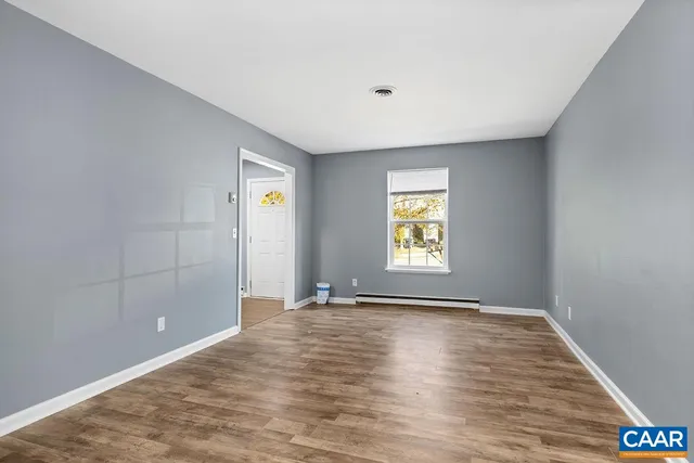 a view of an empty room with window and wooden floor