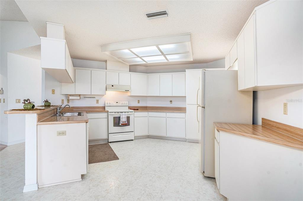 1247 Venetia Drive Spring Hill, FL 34608 - Photo 8 of 27 a kitchen with white cabinets and white appliances