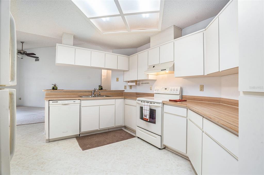 1247 Venetia Drive Spring Hill, FL 34608 - Photo 9 of 27 a kitchen with granite countertop white cabinets and white appliances