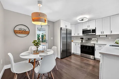 a kitchen with stainless steel appliances a table chairs and a refrigerator