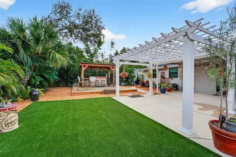 a view of a patio with table and chairs potted plants and large tree