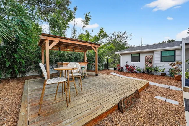a view of a patio with table and chairs potted plants with wooden floor and fence