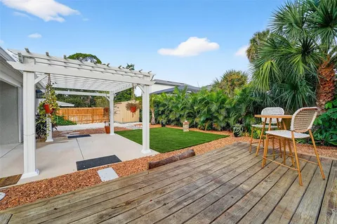 a view of a patio with table and chairs with wooden floor and fence