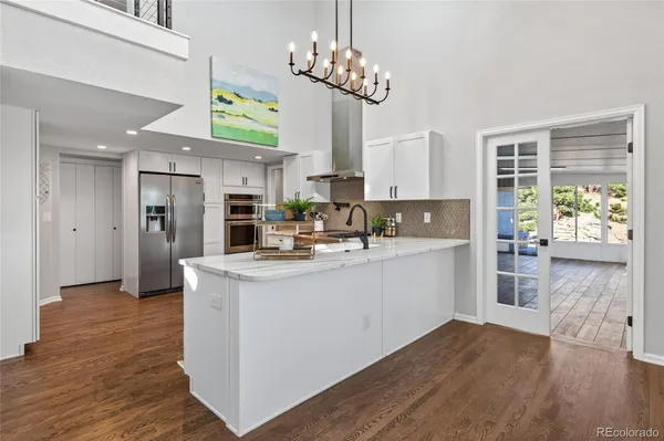 a kitchen with stainless steel appliances granite countertop a refrigerator a stove top oven a sink dishwasher and wooden floor