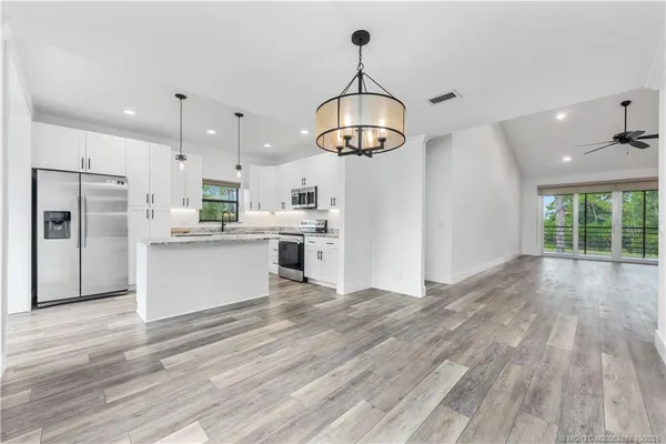 a view of a kitchen with stainless steel appliances granite countertop a refrigerator a stove and a wooden floors