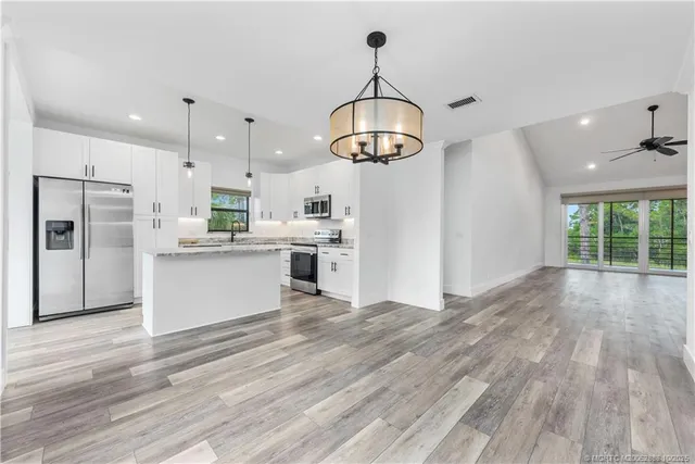 a view of a kitchen with stainless steel appliances granite countertop a refrigerator a stove and a wooden floors