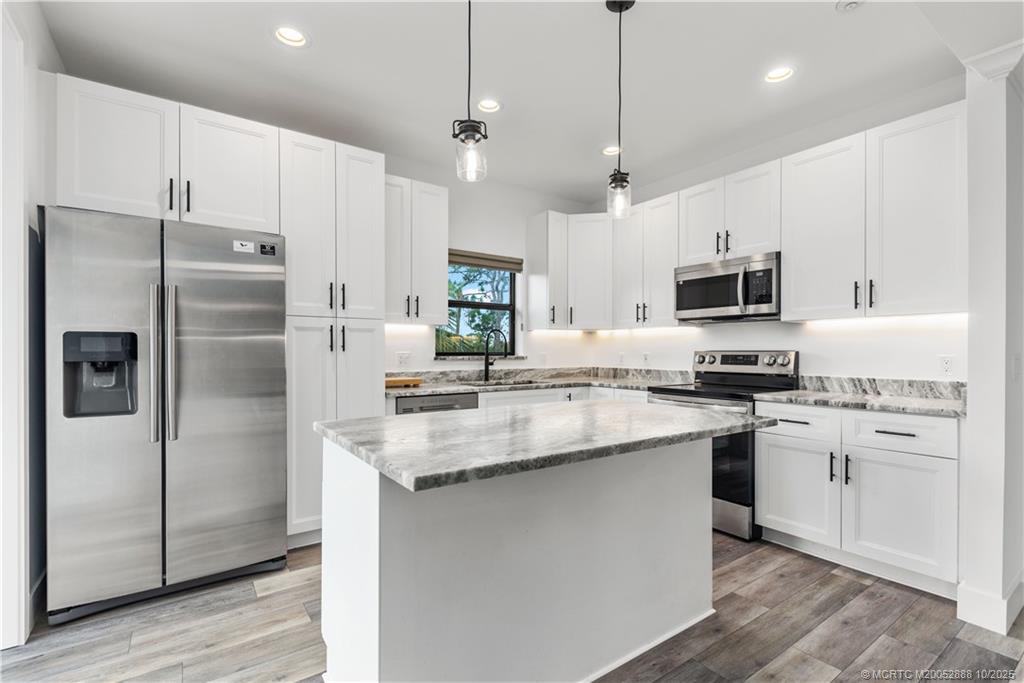 13468 Northwest Harbour Ridge Boulevard, Unit 2A Palm City, FL 34990 - Photo 12 of 38 a kitchen with stainless steel appliances granite countertop a refrigerator a sink dishwasher a stove and white cabinets with wooden floor