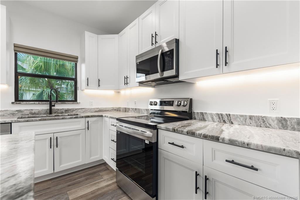 13468 Northwest Harbour Ridge Boulevard, Unit 2A Palm City, FL 34990 - Photo 13 of 38 a kitchen with stainless steel appliances granite countertop a sink and a stove