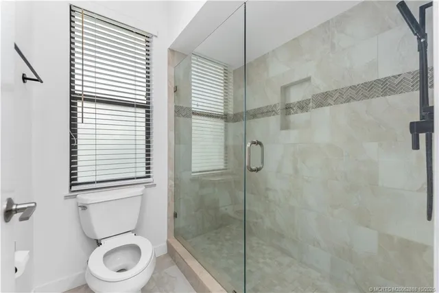 a white toilet sitting next to a shower