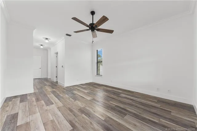 a view of empty room with wooden floor and ceiling fan